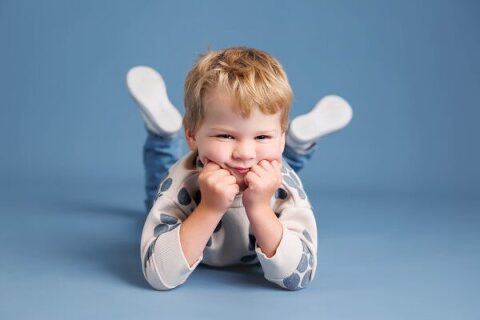 young boy laying on his belly with his chin in his hands