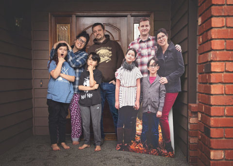 family standing on front porch with cardboard cutout of themselves